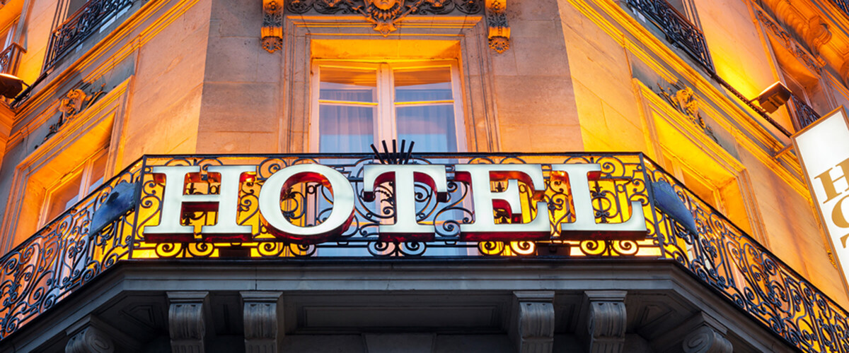 A beautiful balcony, dramatically lit, with the letters "HOTEL" on its ornate railing